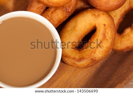 Coffee cup and oil donuts on a wooden plate