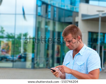 Business man speaking on phone in front of modern business building.