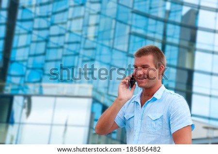 Business man speaking on phone in front of modern business building.