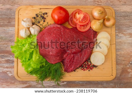 raw beef meat with vegetables on wooden plate