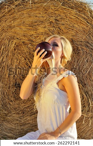 Happy woman drinking milk from cruse or crock and hay as background