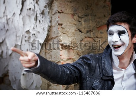 Guy mime against an old brick wall. Indicates the direction of finger
