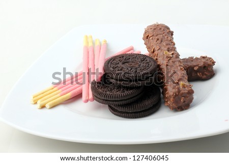 Piles of chocolate chip cookies and chocolate brown long and sticks isolated on a white background.