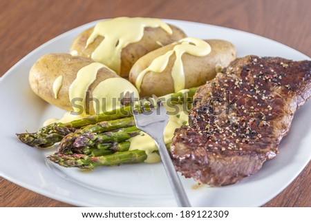 Green Asparagus with potatoes, beef and hollandaise sauce on a white plate