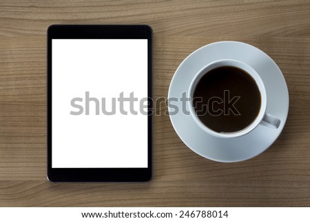 A tablet computer with a white screen and a cup of coffee on a wooden desktop