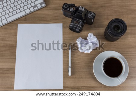 A blank sheet a modern keyboard a vintage camera and a cup of coffee on a wooden desktop