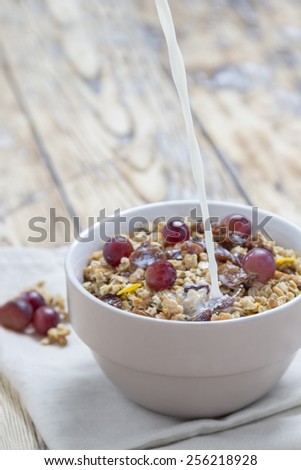 Milk pouring in a bowl with Cereals on a rustic wooden table