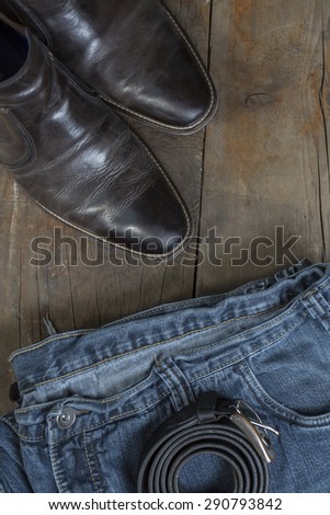 Jeans, Belt and leather boots, on a rustic wooden background
