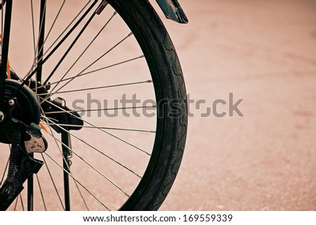 a photo of close up old-fashioned bicycle  wheel side walk way