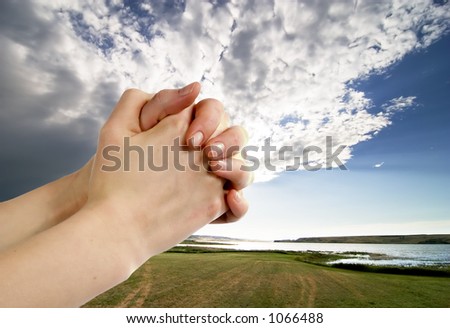 A pair of hands in a praying position set against a beautiful prairie lake landscape