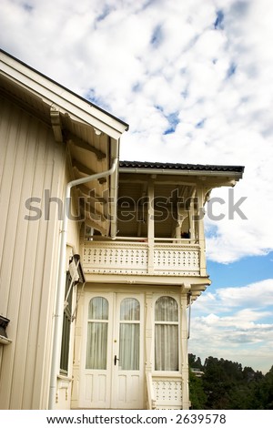 An old swiss style villa in south eastern norway against a blue sky with clouds.