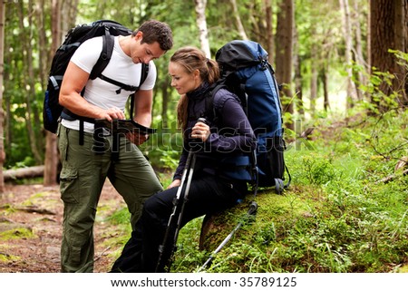 A couple of backpackers looking at a map in the forest
