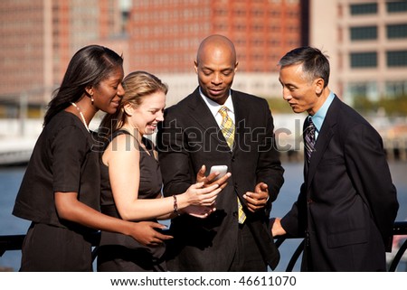 A group of business people crowded around a cell phone