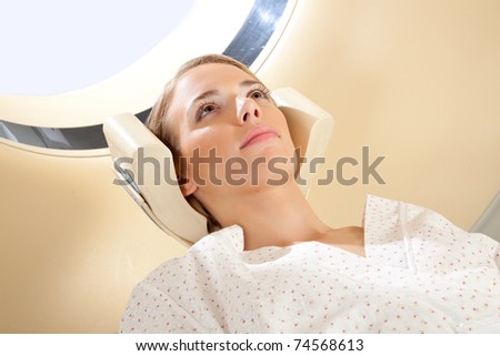 A young woman with eyes open preparing for a CT scan
