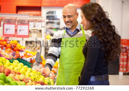 A woman buying groceries receiving help from a store clerk