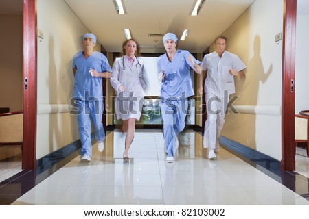 Team of surgeon and nurse running in hallway of hospital