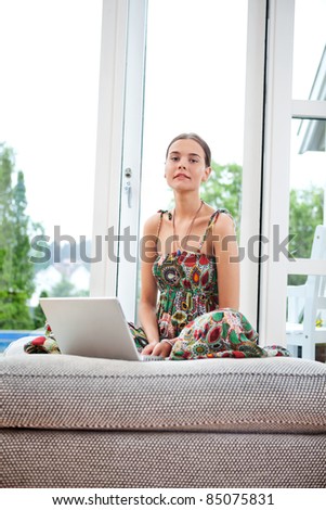 Portrait of young woman with laptop on couch