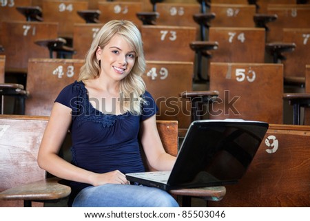 Portrait of sweet young college girl using laptop in university lecture hall