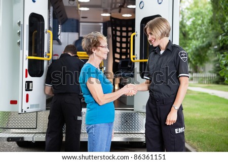 Ambulance staff shaking hands with elderly patient