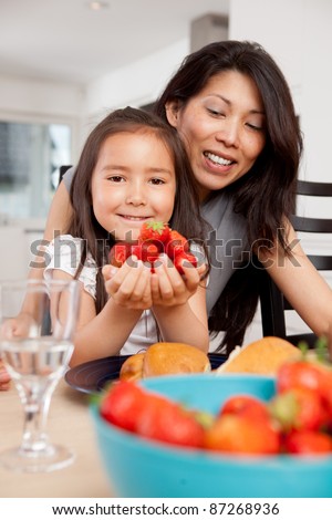 Smiling mother and daughter with fresh picked strawberries