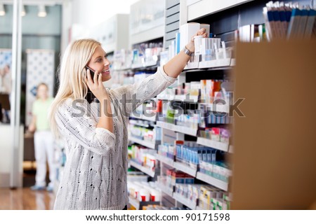 Female talking on cell phone while looking for medicines at drugstore