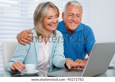 Mature woman having tea and browsing internet with her husband on laptop