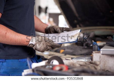 Detail of a mechanic holding a service order with a dirty glove on