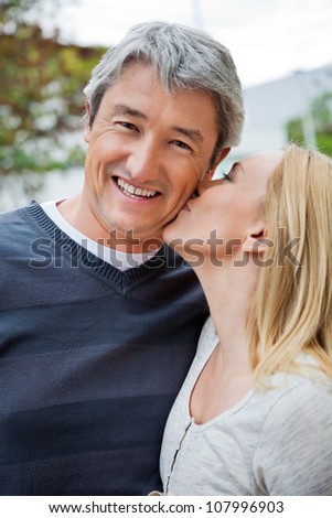 Blond woman kissing a cheerful middle aged man
