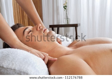 Young shirtless man receiving massage from masseur at health spa