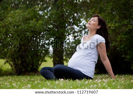 Relaxed calm pregnant woman in third trimester in park with eyes closed