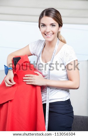Female dressmaker adjusting clothes on tailoring mannequin.