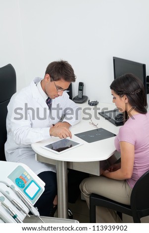 Female patient with doctor using tablet PC at desk in dental clinic