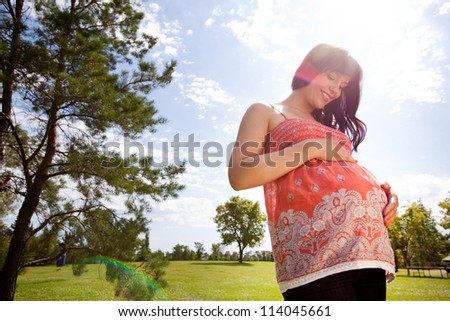 Attractive pregnant woman outdoors in park - shot towards sun with lens flare