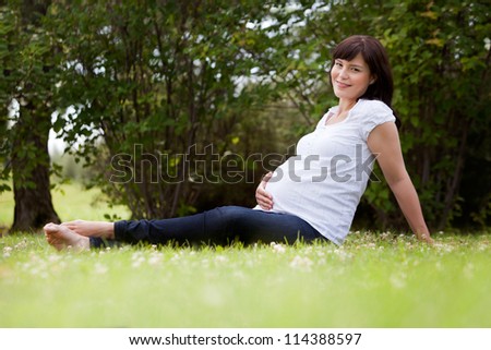 Portrait of a pregnant woman in third trimester relaxing in park