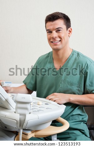 Portrait of happy young male technician operating ultrasound machine