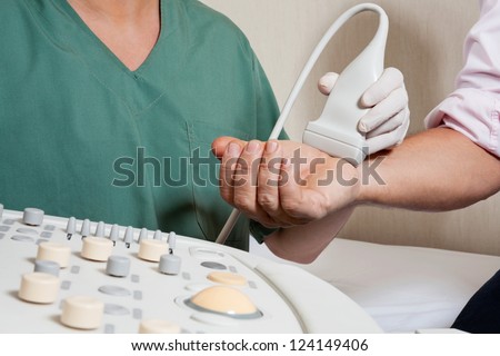 Midsection of radiologic technician scanning male patient\'s hand