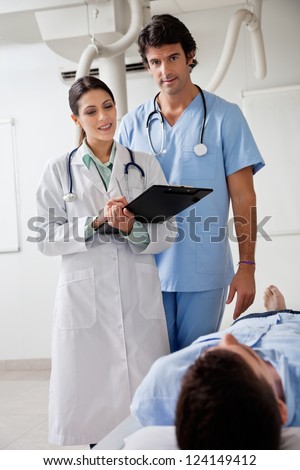Portrait of male technician with female doctor noting down notes of patient