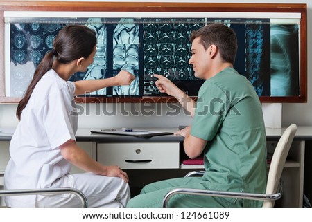 Two medical technicians pointing at MRI x-ray of patient
