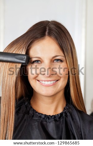Portrait of happy mid adult woman straightening hair