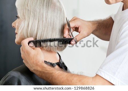 Closeup of male hairstylist measuring hair length before haircut in parlor