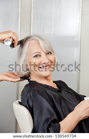 Portrait of happy senior woman getting hair styled in salon