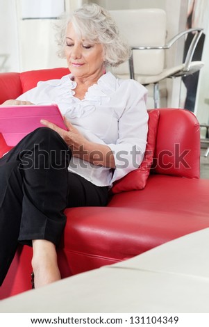 Senior female client using digital tablet at salon