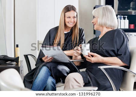 Female client\'s with magazine and cup conversing at beauty parlor