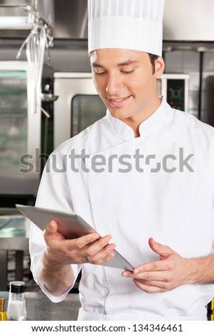 Handsome chef using digital tablet in commercial kitchen