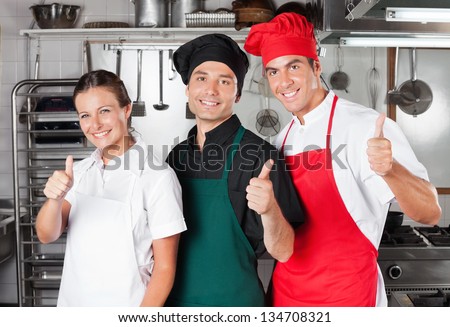 Team of chefs giving thumbs up in restaurant kitchen