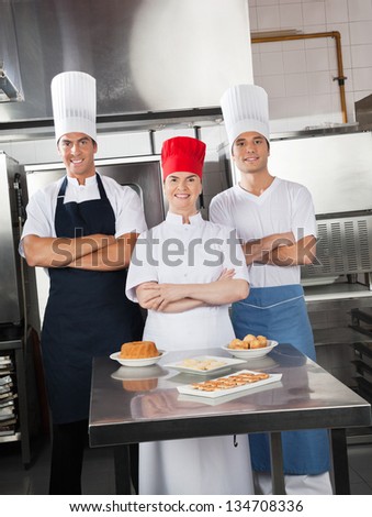Portrait of confident chefs with sweet dishes on commercial kitchen counter