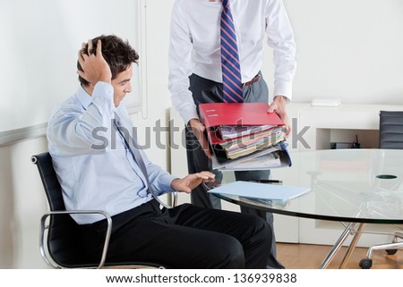 Young businessman at desk overwhelmed by load of work