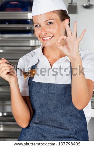 Portrait of female chef appreciating chocolate cream with okay sign
