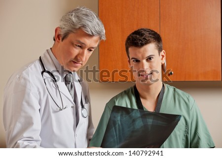 Portrait of male technician with mature doctor reviewing shoulder x-ray