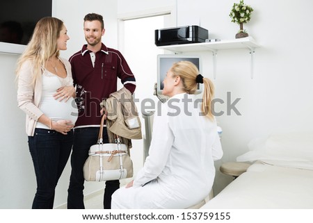 Young expectant couple looking at each other during a visit to obstetrician in clinic